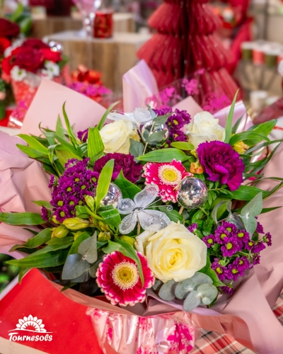 Bouquet coloré de Noël avec roses blanches et éléments décoratifs argentés.